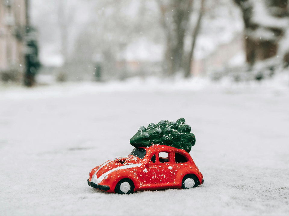 Spielzeugauto mit Weihnachtsbaum im Schnee