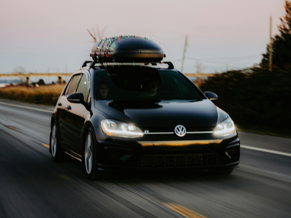 Ein schwarzer VW mit Dachbox fährt auf der Autobahn entlang.