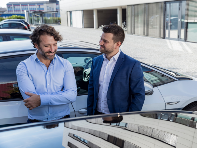 Zwei Männer unterhalten sich vor einem Auto